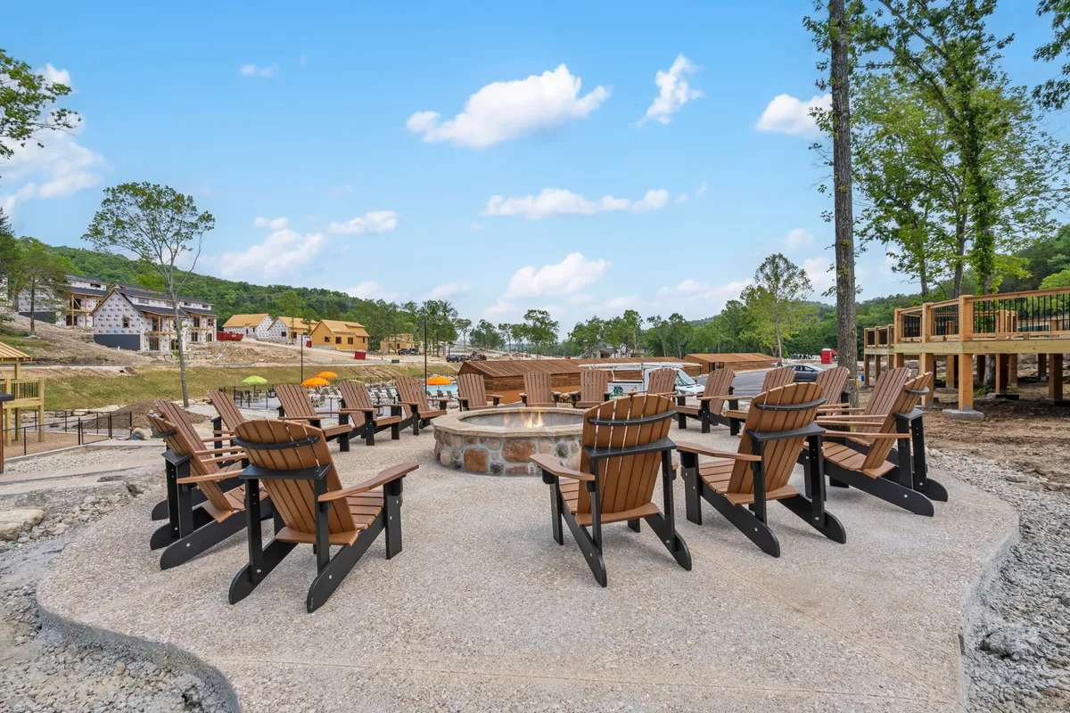 A classic fire pit ringed by Adirondack chairs in a scenic outdoor environment, inviting guests to gather for s'mores, storytelling, and stargazing. The relaxed configuration encourages communal experiences and evening connection.