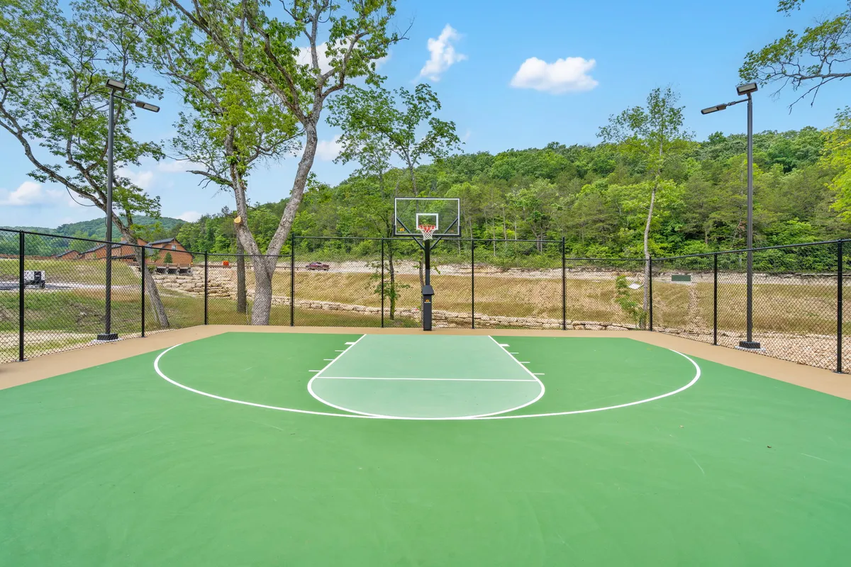 This exterior image highlights a basketball court bordered by trees and a mountain backdrop, conveying a sense of active energy and open-air fun. Families and friends can be seen playing basketball, taking advantage of the sports amenities.