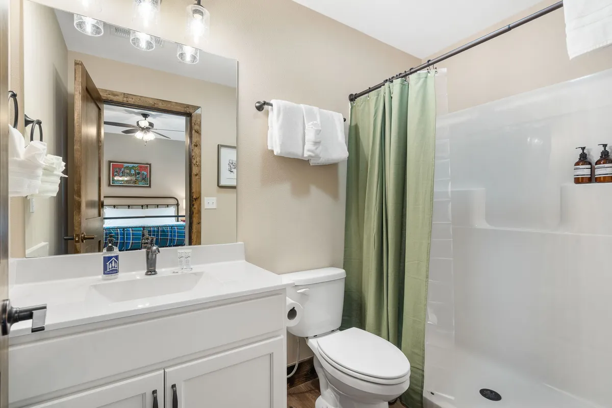 A serene ensuite bathroom with a vanity and sink, walk-in shower, toilet, and a large mirror. The well-lit space offers a sense of freshness and relaxation, ideal for unwinding in privacy.