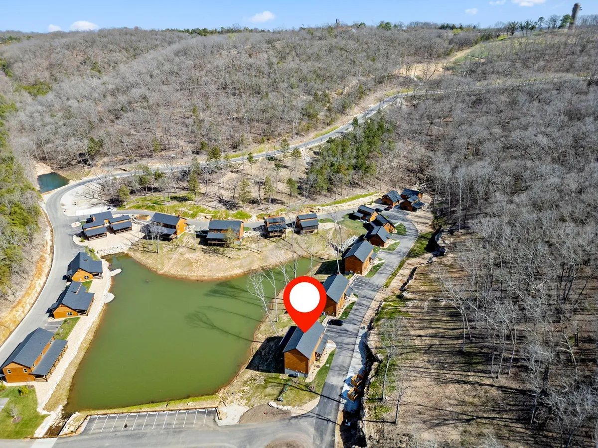 A tranquil exterior view of the property’s cabins and pond, with the surrounding landscape offering a peaceful backdrop. Guests can be seen enjoying fishing and relaxing by the water, emphasizing the connection to nature and outdoor adventure.